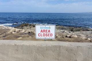 Signage along the concrete wall that lines Point La Jolla directs people away from the bluffs.