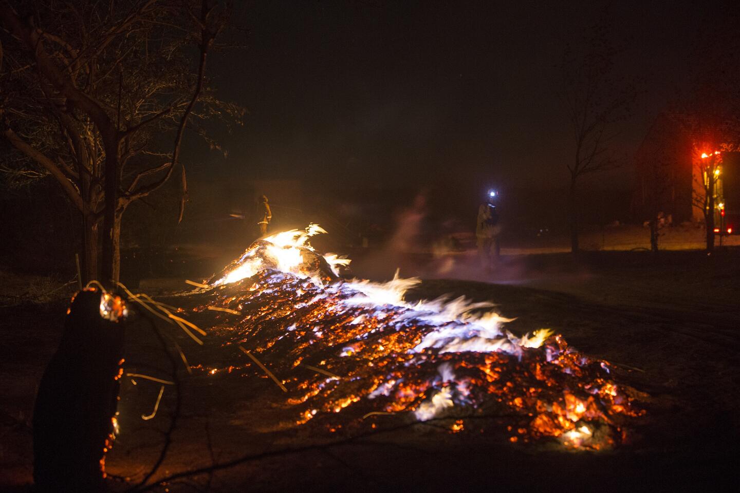 Firefighters use small headlamps at night to battle flames from the 3,500-acre brush fire after it ripped through the Cajon Pass and headed north July 17, 2015, in Baldy Mesa, Calif.