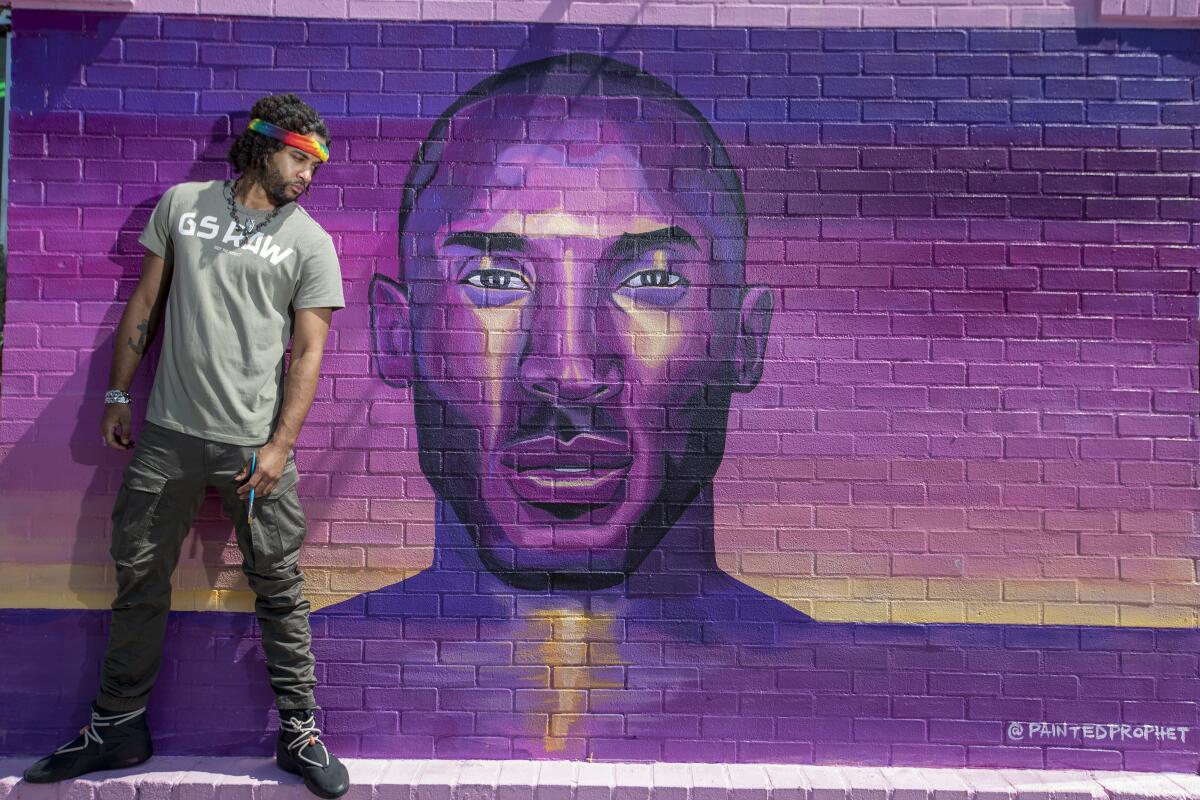 Artist Josh McCadney stands in front of a Kobe Bryant mural he painted at Sorella Boutique.