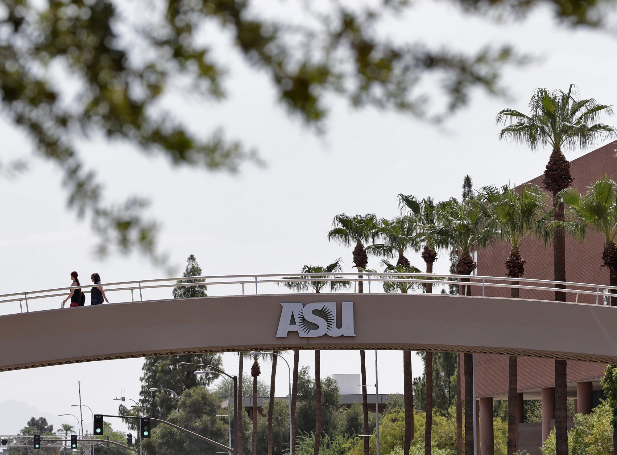 Pedestrians cross over University Avenue on the campus of Arizona State University.