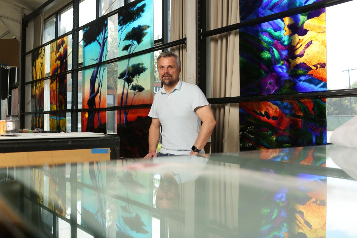 David Judson in front of fused-glass landscapes in his company's studio.