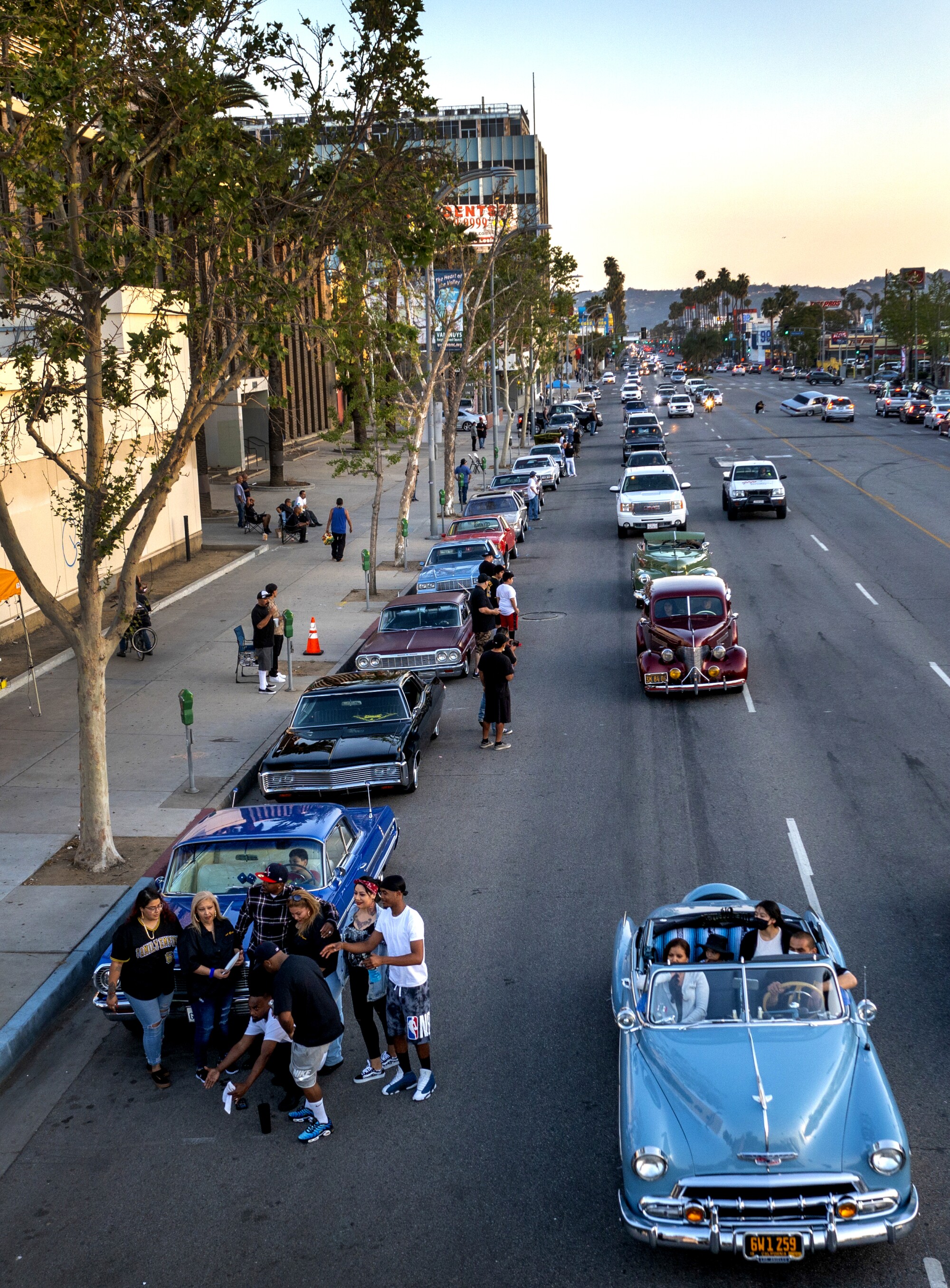People gather along Van Nuys Boulevard to watch vintage cars cruise by