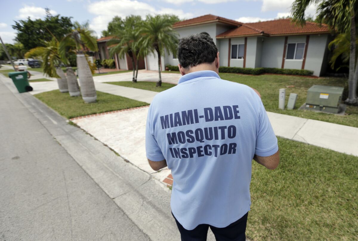 An inspector with a county mosquito control unit walks door to door while responding to a complaint about mosquitoes in Miami, Fla. on April 12.