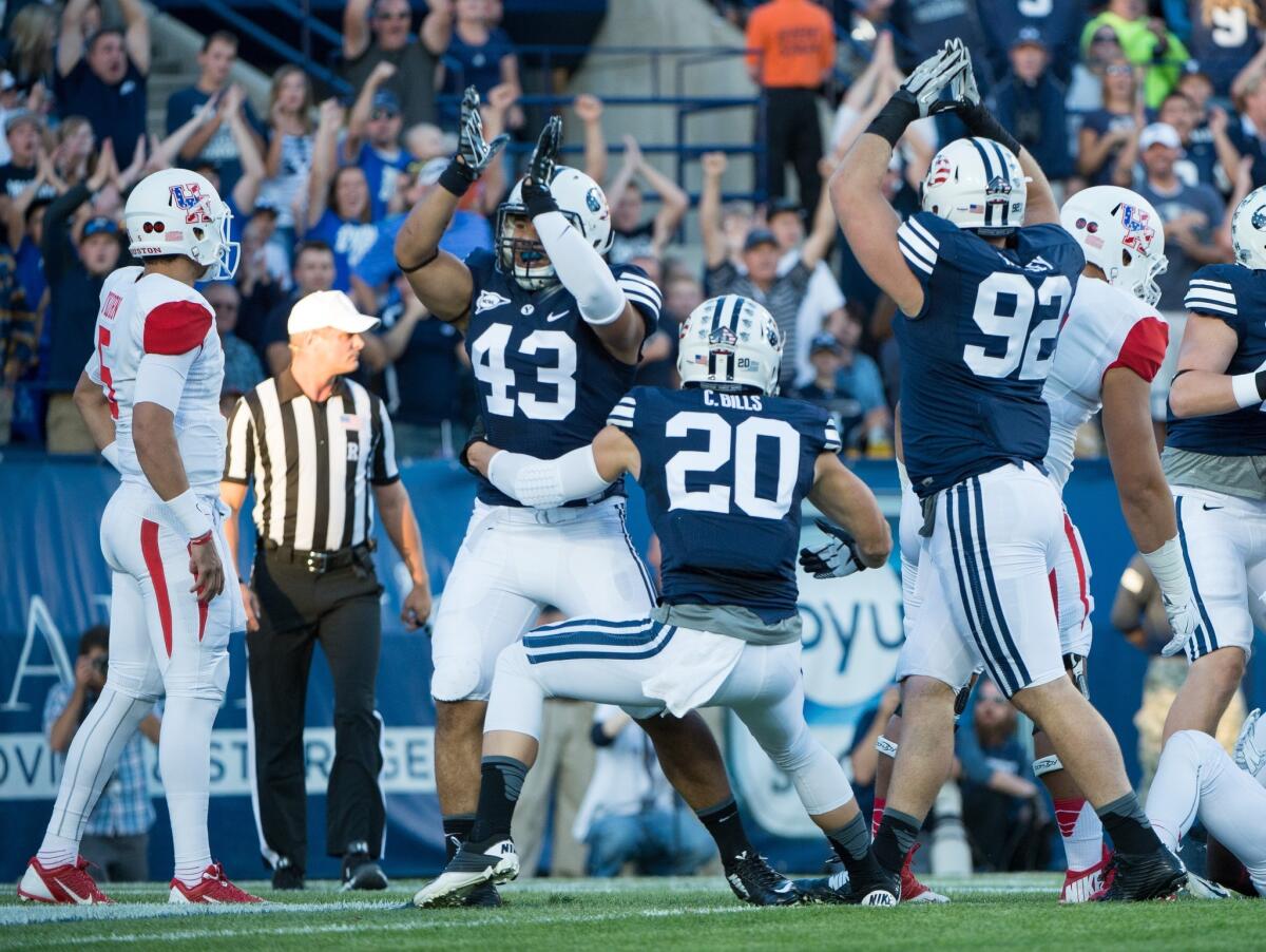 Houston quarterback John O'Korn, left, watches as Jherremya Leuta-Douyere (43), Craig Bills (20) and Graham Rowley (92) of Brigham Young celebrate a safety in the first quarter. BYU beat Houston, 33-25.