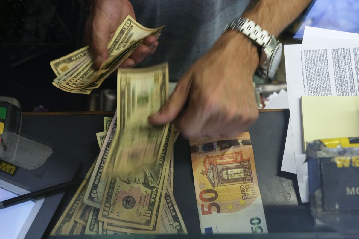 FILE - A cashier changes a 50 Euro banknote with US dollars at an exchange counter in Rome, Wednesday, July 13, 2022. Europe's feeling the pain from the war in Ukraine. More so than the U.S., the 19 countries that use the euro are under pressure from high oil and gas prices. While Europe struggles, Russia has stabilized its currency and inflation - but economists say that's misleading and that the Kremlin has bought itself long-term stagnation by launching the war. (AP Photo/Gregorio Borgia, File)