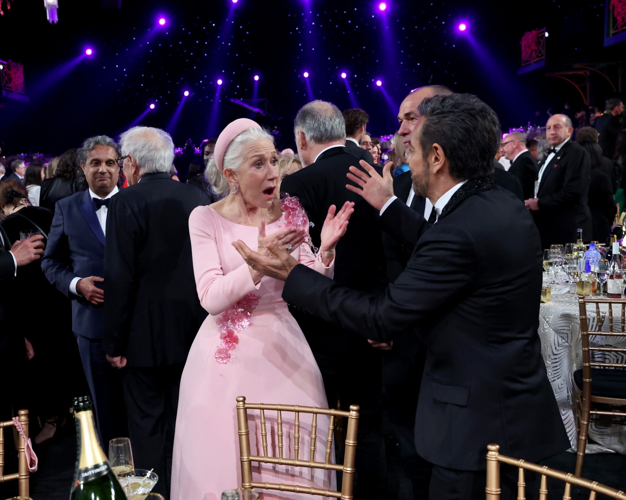 Helen Mirren and Eugenio Derbez lift their arms to each other during the SAG Awards.