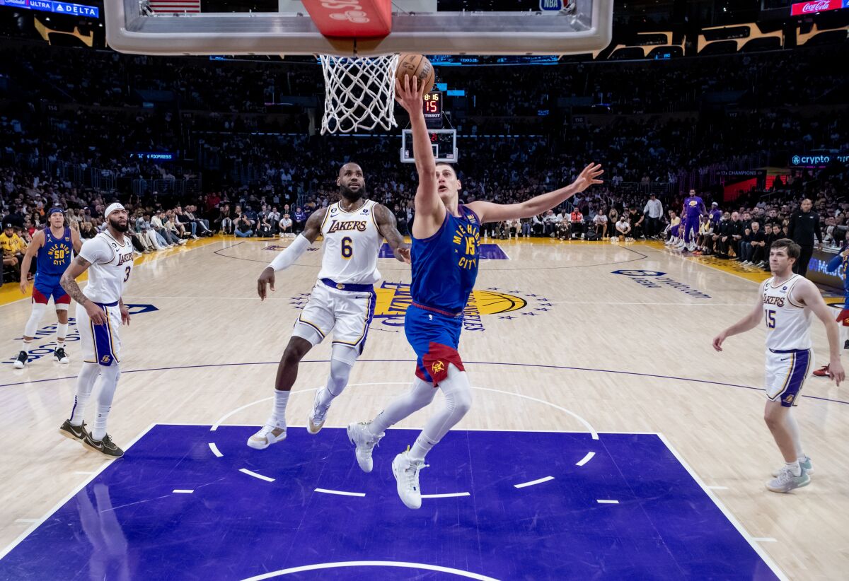 Nuggets center Nikola Jokic scores easily on a layup past Lakers forward LeBron James.