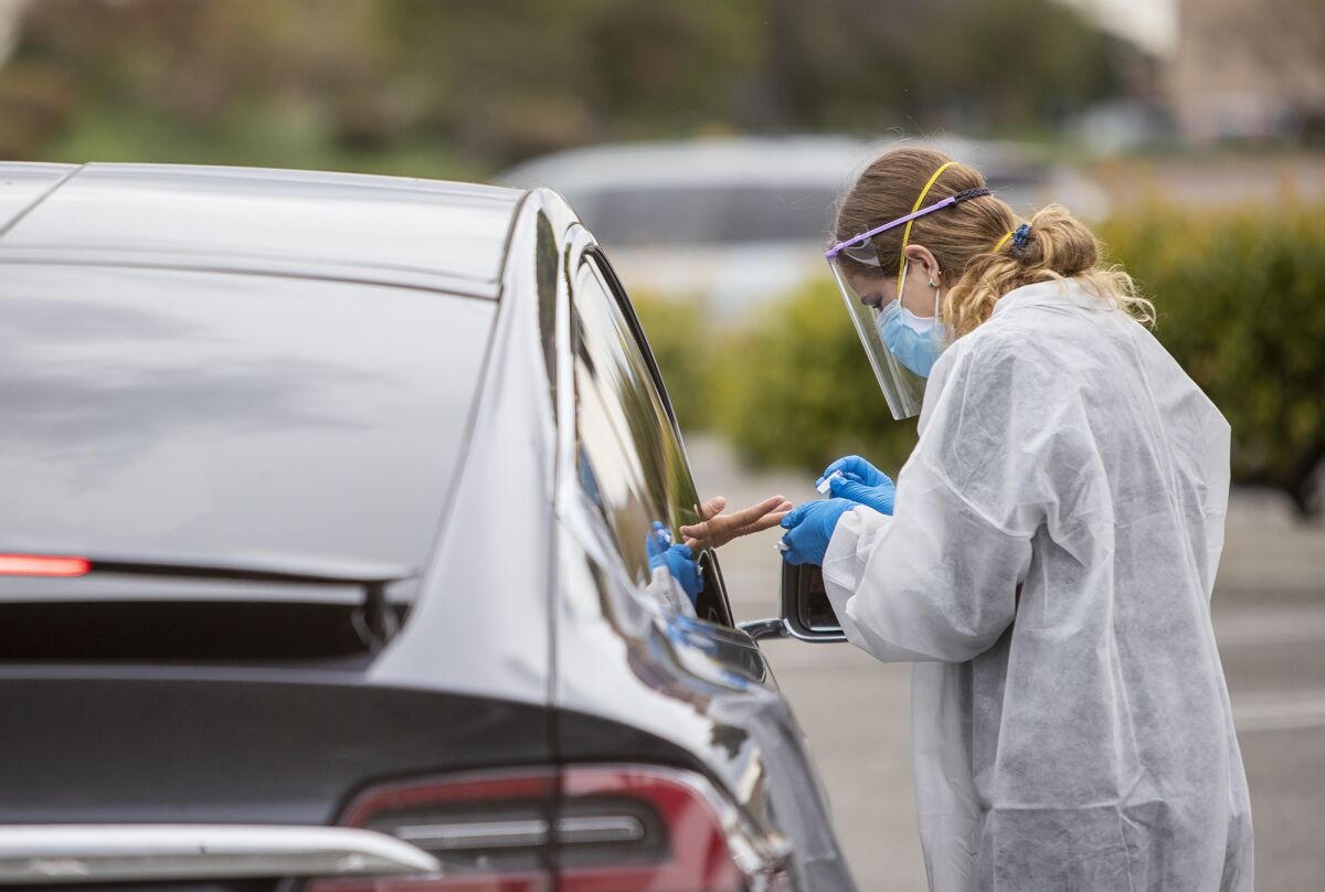 A health care professional tests a driver for the antibody test for COVID-19 at a drive-through testing site at the Westminster Mall on April 7.