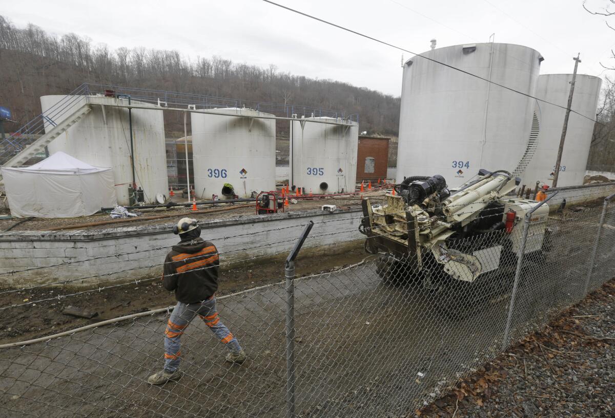 A worker moves a drilling machine around tanks at Freedom Industries' storage facility in Charleston, W.Va.
