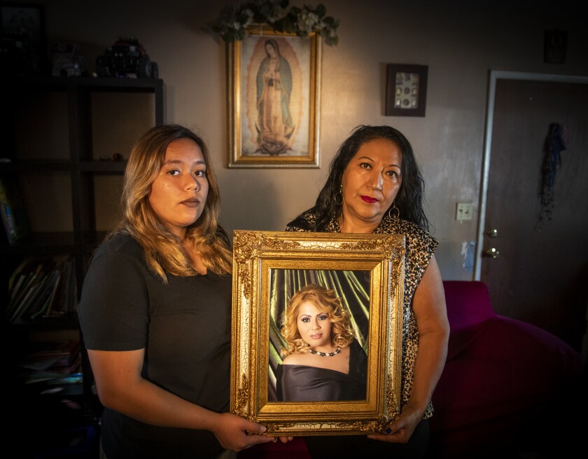 Melody and Herlinda hold a portrait of their mother and daughter