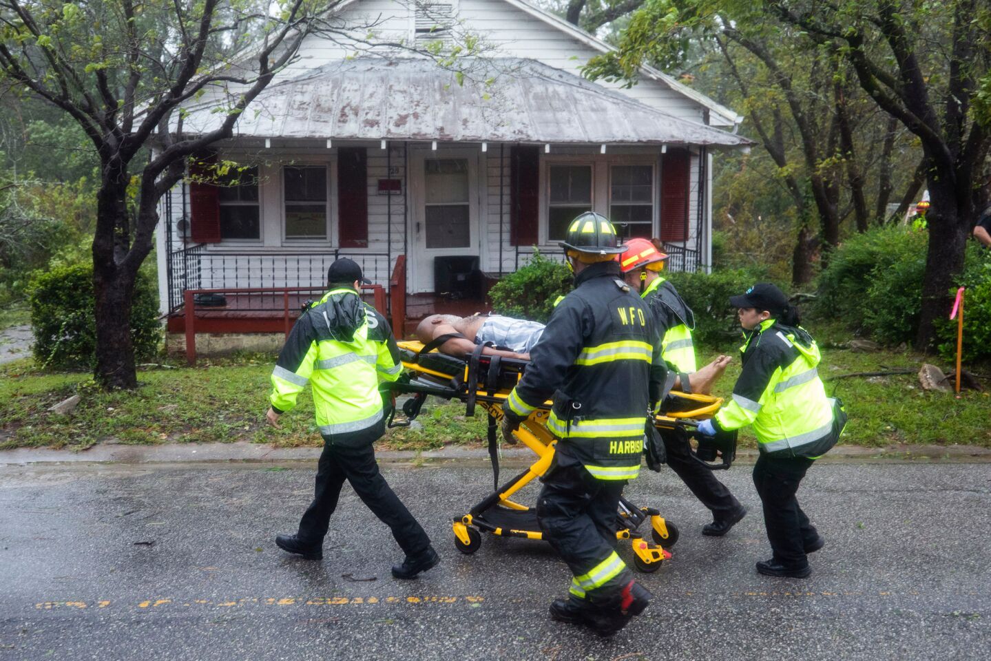 Rescue workers rush a man to an ambulance after a giant tree toppled onto his house, killing two other people when Hurricane Florence came ashore in Wilmington, N.C.