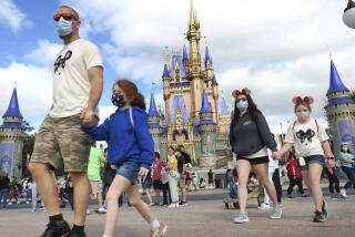 FILE - IN this Dec. 21, 2020 file photo, A family walks past Cinderella Castle in the Magic Kingdom, at Walt Disney World in Lake Buena Vista, Fla. To help celebrate the 50th anniversary of the opening of Walt Disney World in Florida, Mickey and Minnie are getting flashier threads and iconic structures such as Cinderella's Castle and the Tower of Terror are getting new lighting. Disney officials on Friday, Feb. 19, 2021, unveiled the first details on how Disney World will celebrate its milestone anniversary.(Joe Burbank/Orlando Sentinel via AP, File)