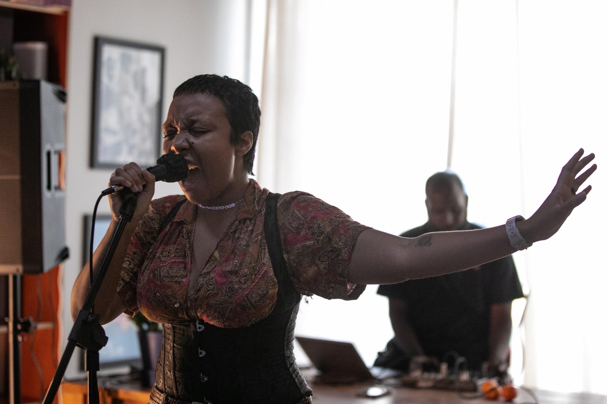A Black woman sings into a microphone.