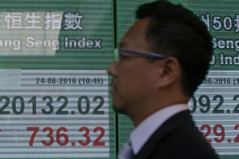 A man passes a screen showing the Hang Seng index in Hong Kong on June 24.