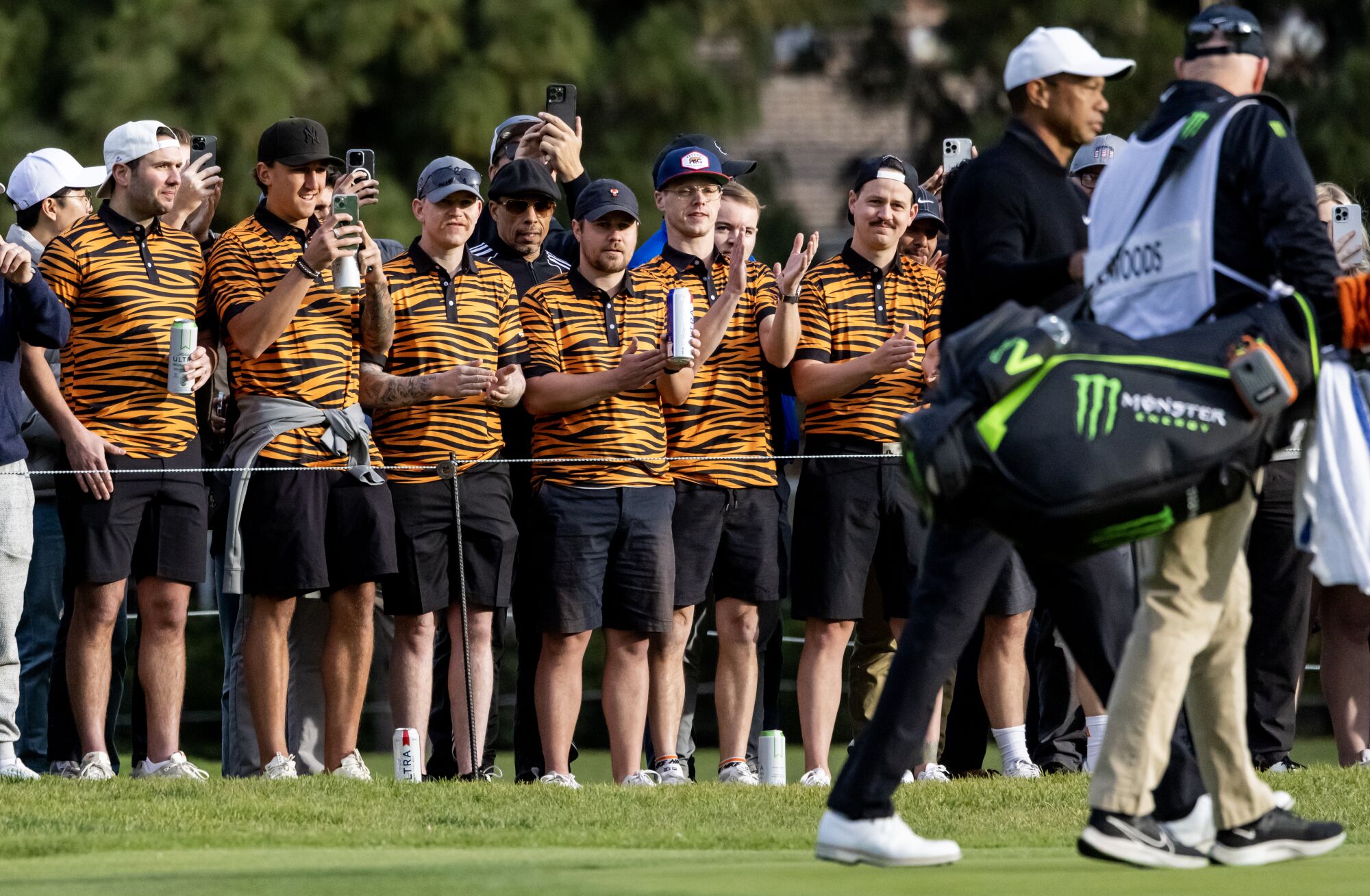 A group dressed in tiger colored polo shirts line the 11th fairway as Tiger Woods passes by during round two.