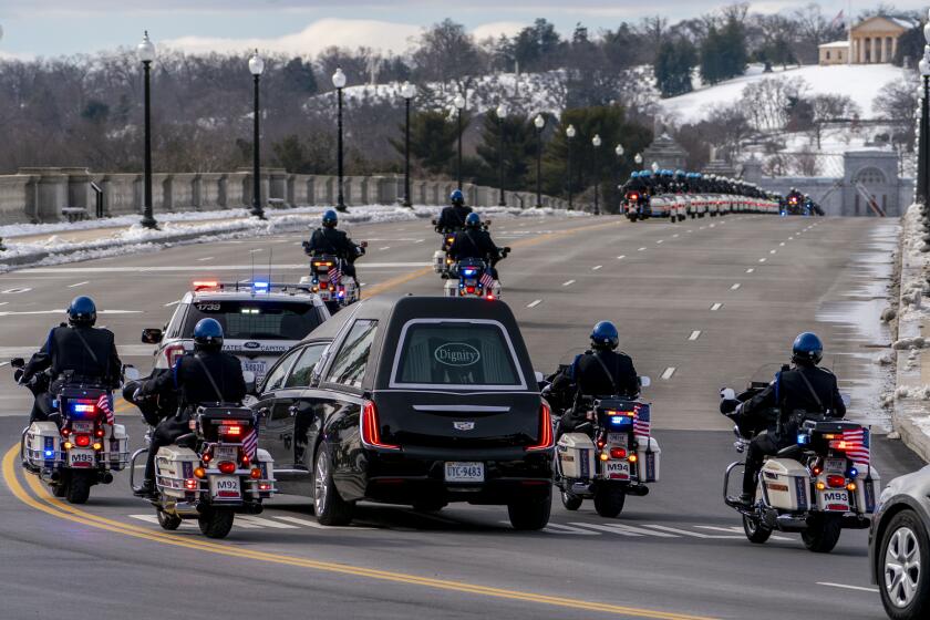 FILE - In this Feb. 3, 2021 file photo, a hearse carrying the remains of U.S. Capitol Police officer Brian Sicknick makes its way to Arlington National Cemetery after Sicknick was lying in honor at the U.S Capitol, Wednesday, Feb. 3, 2021, in Washington. (AP Photo/Andrew Harnik)