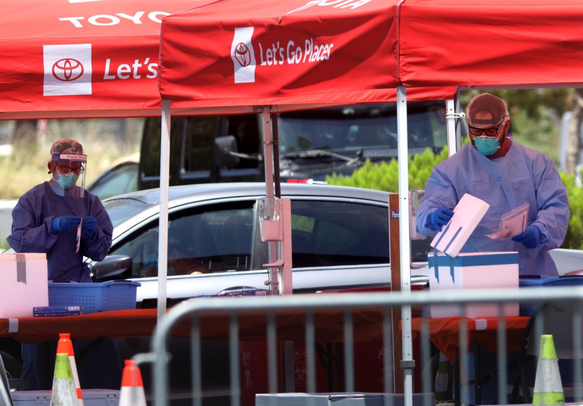 Workers at a COVID-19 testing site in the parking lot at the Banc of California Stadium in Los Angeles.