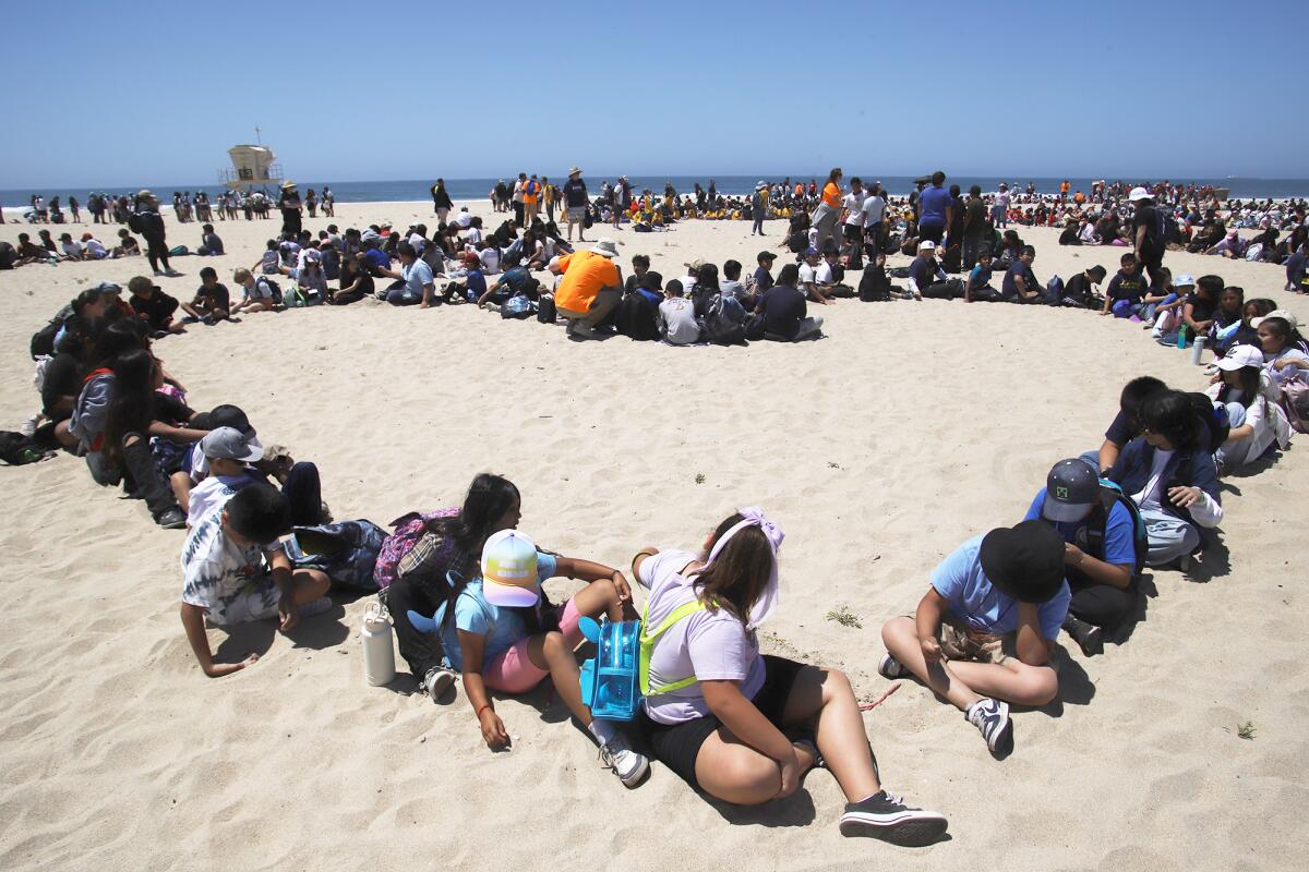 Orange County elementary students sit on the sand to create a massive aerial art display at Huntington State Beach.
