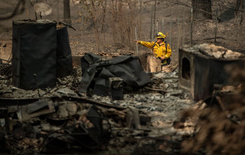 Firefighters search through a burned-out residence near Berry Creek.