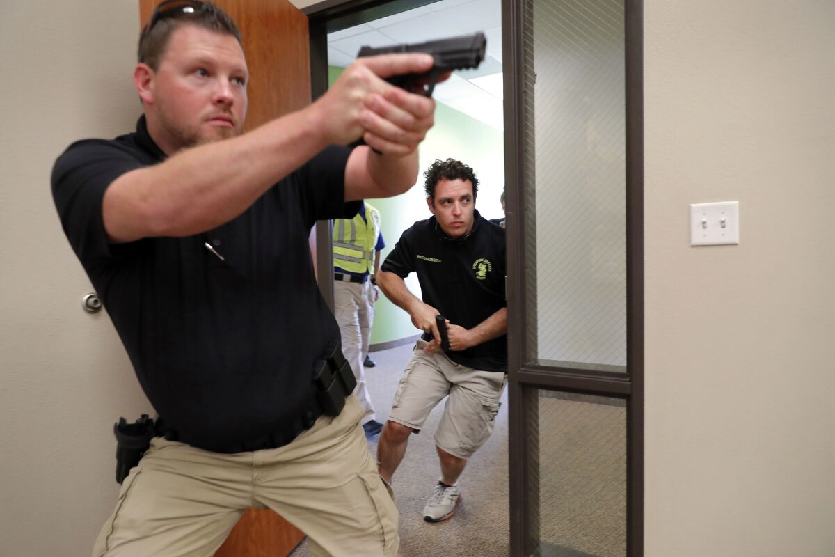 FILE - In this July 21, 2019 file photo, trainees Chris Graves, left, and Bryan Hetherington, right, participate in a security training session at Fellowship of the Parks campus in Haslet, Texas. An industry has sprung up following mass shootings at houses of worship around the country to train civilians to protect their churches with the techniques and equipment of law enforcement. (AP Photo/Tony Gutierrez, File)