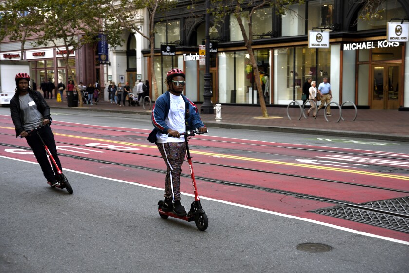 Tourists ride Scoot e-scooters on Market Street in San Francisco.