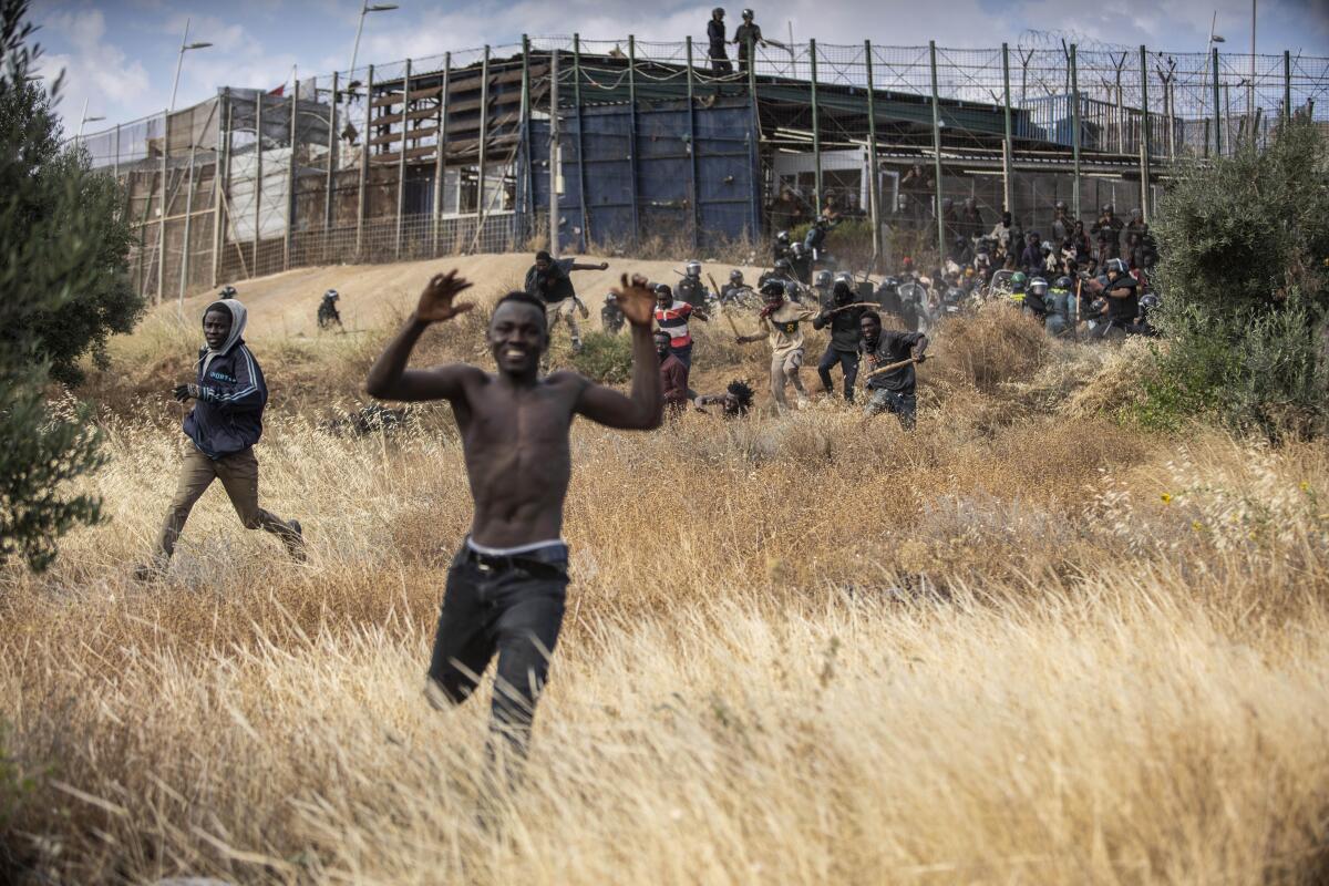 Migrantes emprenden la carrera en suelo español después de cruzar las vallas que separan el enclave español de Melilla