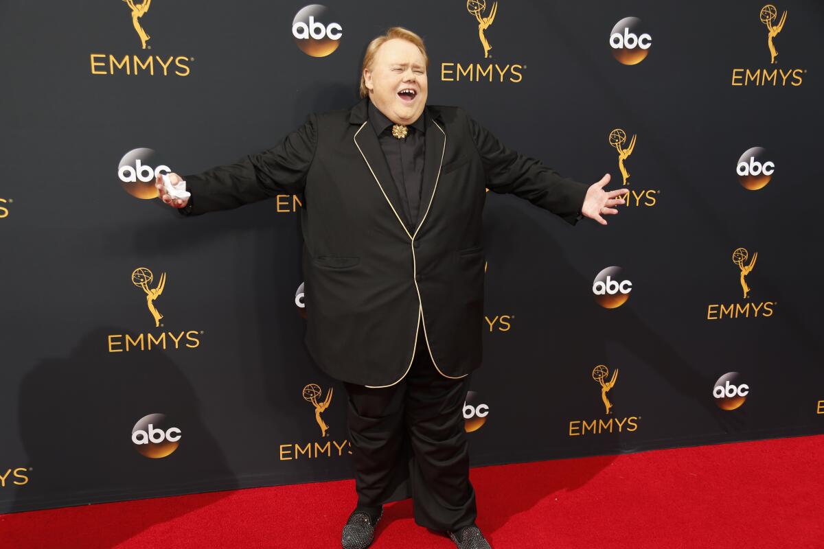 A man in a black suit stands on a red carpet