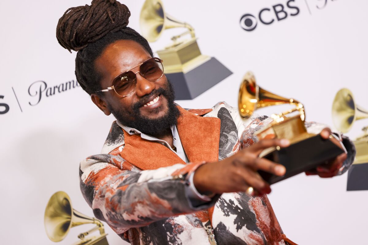 A man holds his Grammy statue towards photographers backstage