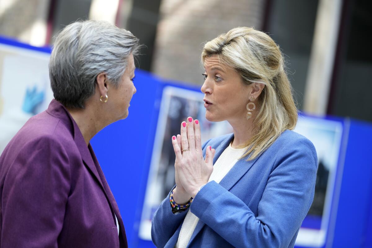 Two women in suits speak with each other.