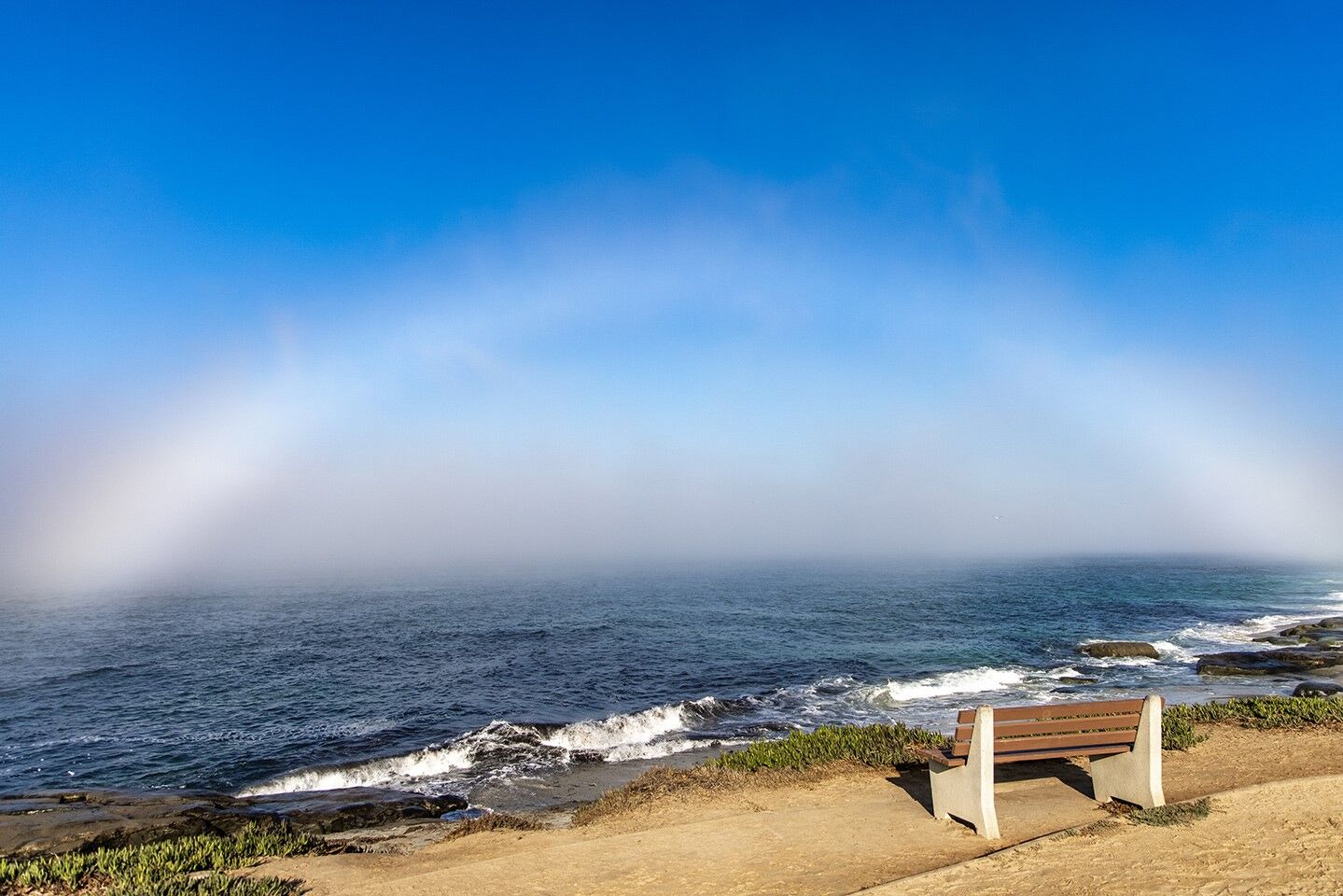 A fog bow, or "ghost rainbow," appears at Windansea, a result of very small water droplets in fog.