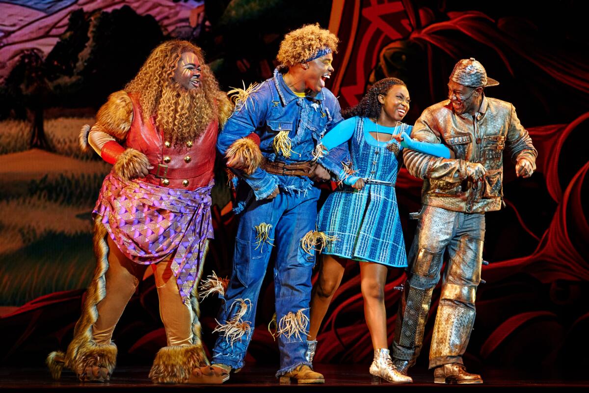 Actors playing a lion, a scarecrow, Dorothy Gale and a tin man link arms