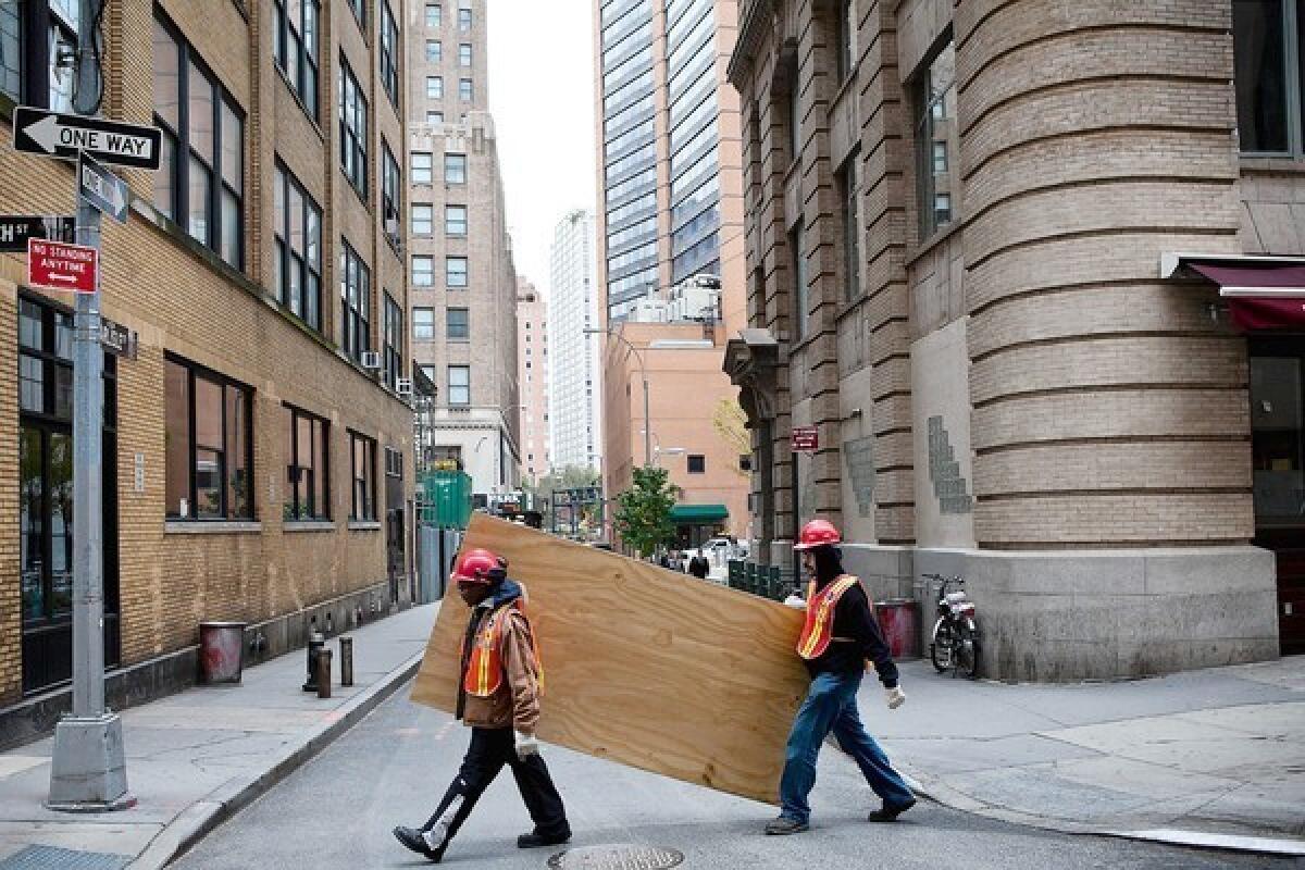 Workers in New York carry boards to cover subway air vents as Superstorm Sandy approached in October.