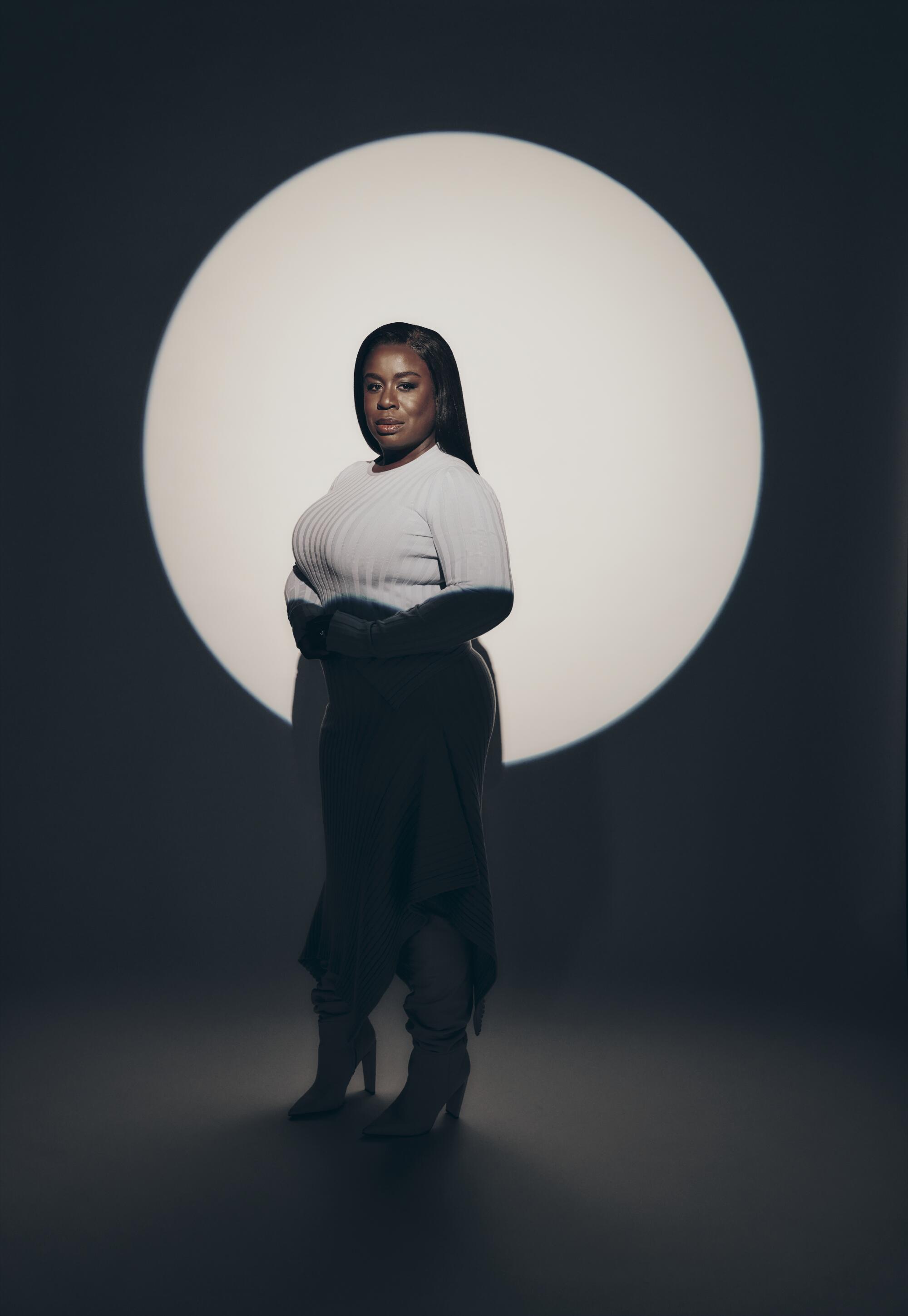A woman standing with her top half illuminated in a circle of light