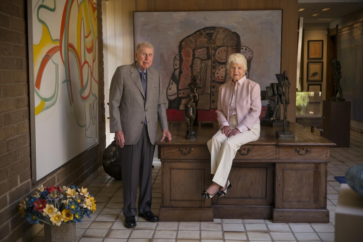 Harry "Hunk" and Mary "Moo" Anderson pose in the foyer of their home with two paintings in the background. The Willem DeKooning, left, and Philip Guston, directly behind them, are both part of a collection they are donating to Stanford University.