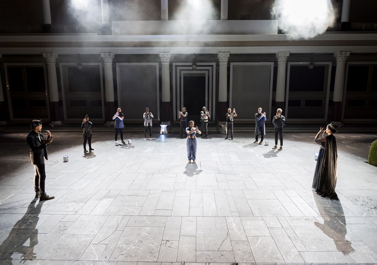 Cast of 'Oedipus' at Getty Villa in a half ring around a person in the center of the stage.
