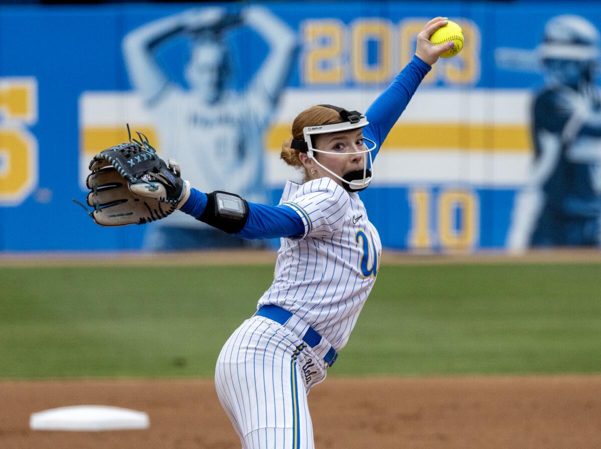 Left-handed pitcher Kaitlyn Terry winds up with a face mask and pinstripe UCLA uniform