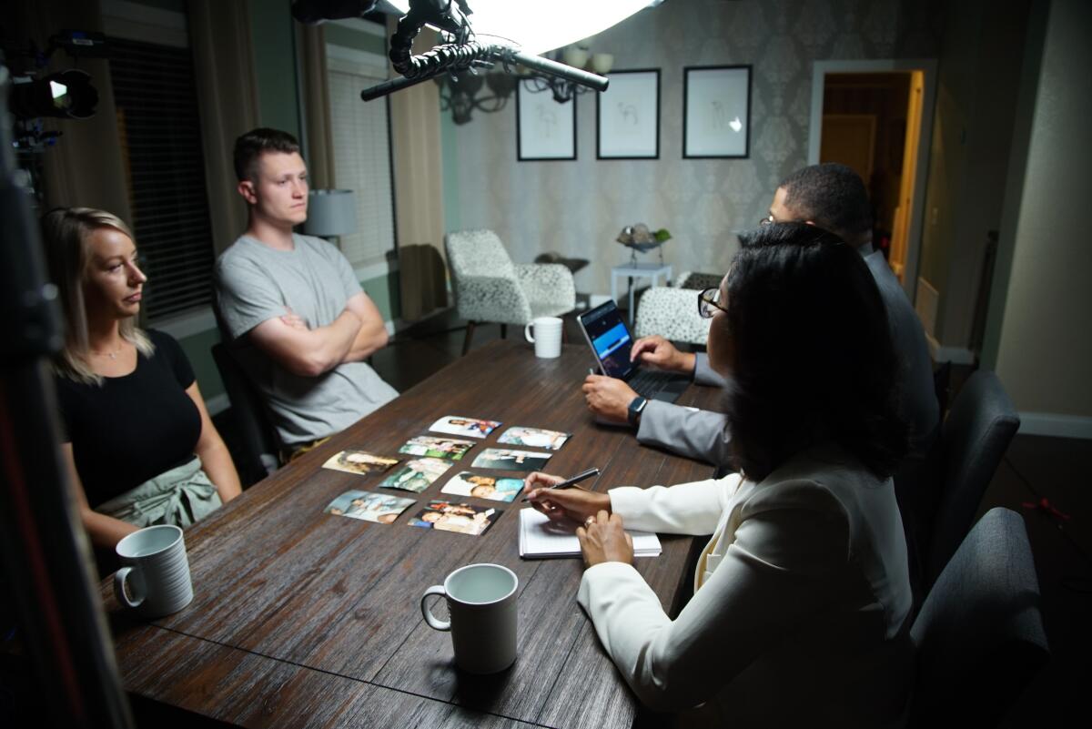 Two men and two women sit at a dining table with photos spread out on its surface.