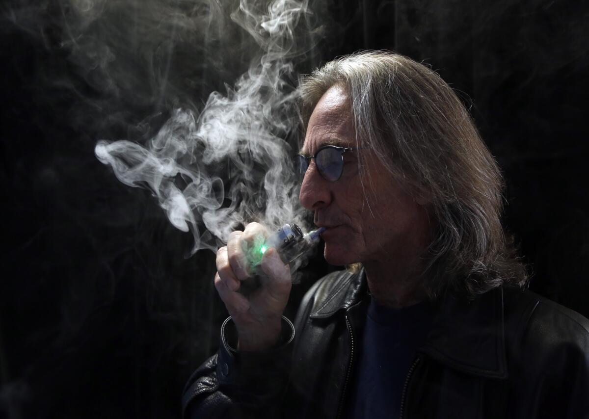 John Hartigan, proprietor of Vapeology LA, a store selling electronic cigarettes and related items, takes a puff of an electronic cigarette at his store in Los Angeles.