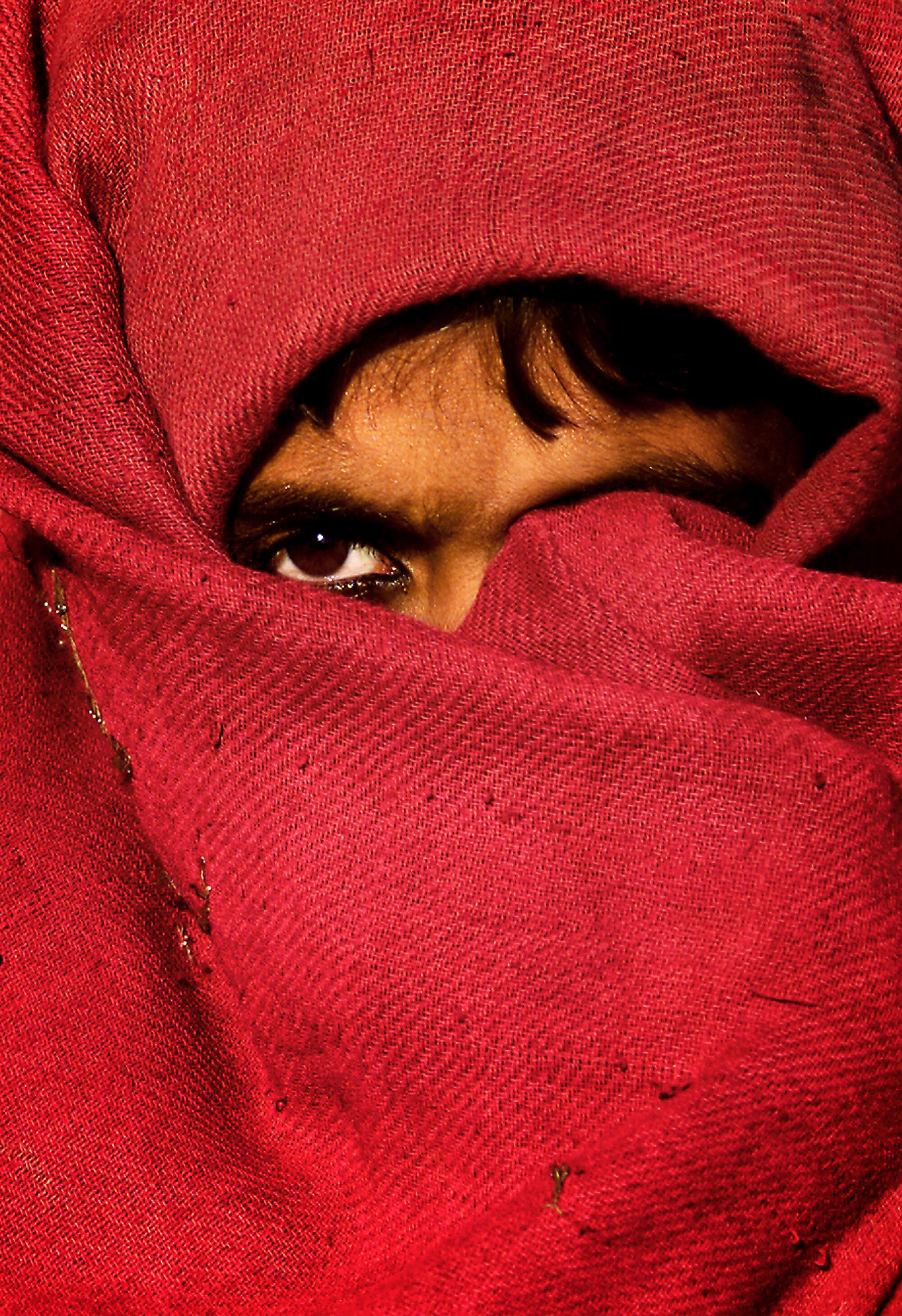 A girl with her face mostly covered by red cloth