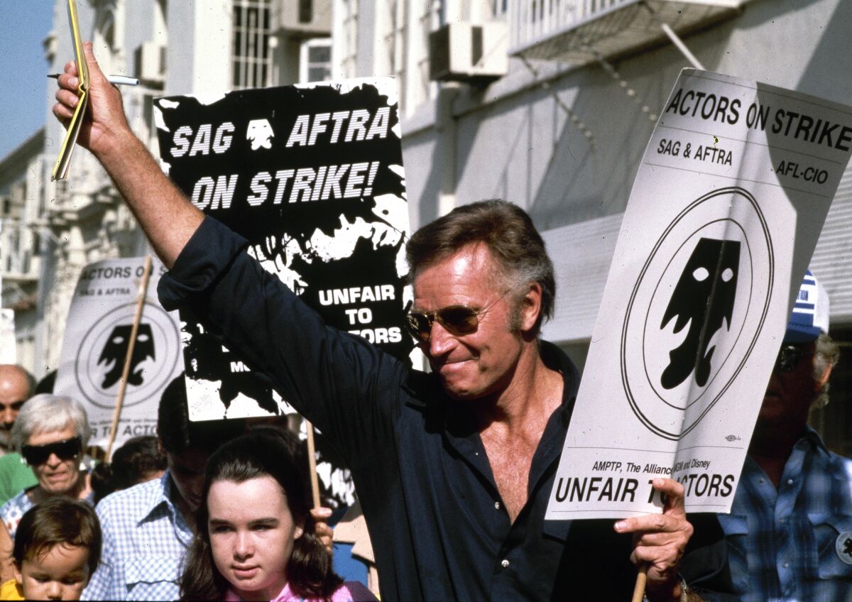 Charlton Heston holds a picket sign and leads a group of strikers.