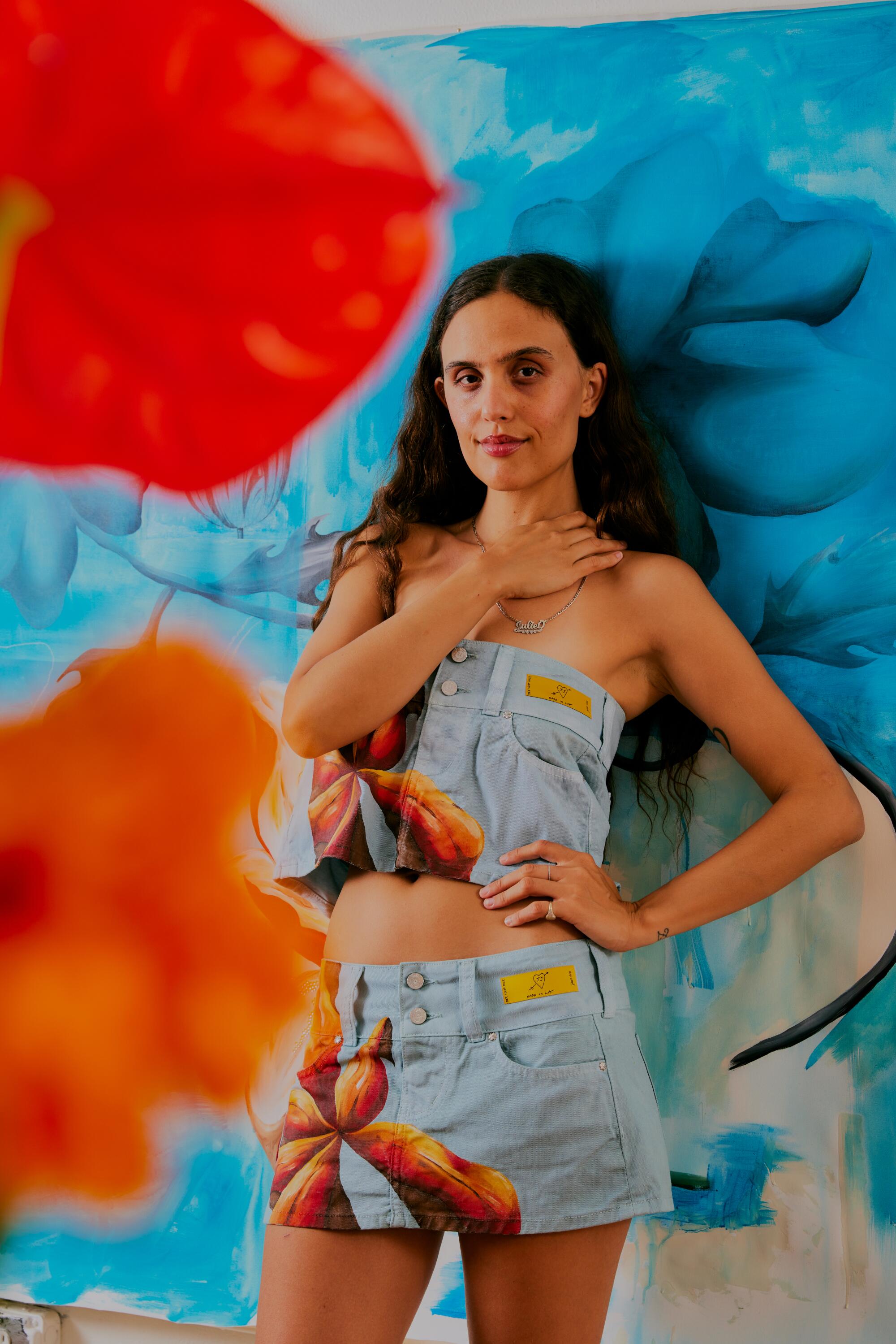 An image of a woman standing before a painting of blue flowers