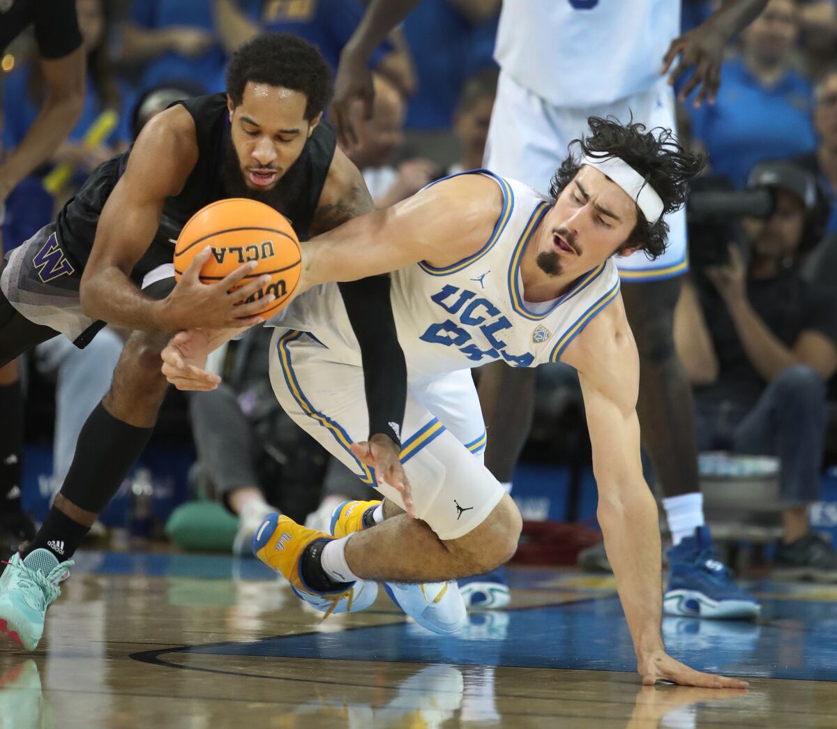 Washington guard PJ Fuller II and UCLA forward Jaime Jaquez Jr. battle for a loose ball.