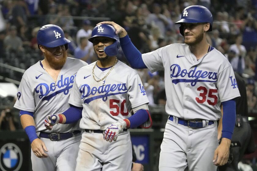 Los Angeles Dodgers' Mookie Betts (50) celebrates with Justin Turner and Cody Bellinger.