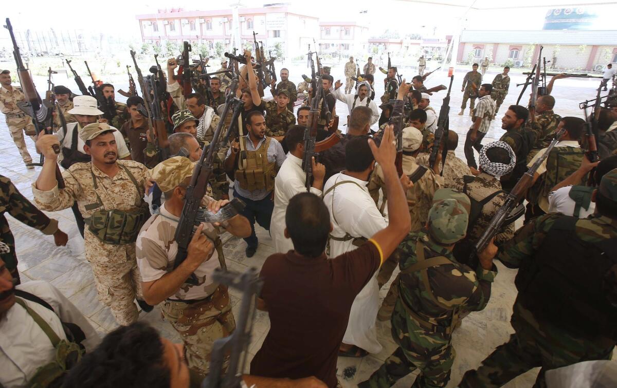 Shiite Muslims parade with their weapons in the Iraqi shrine city of Karbala on June 25.