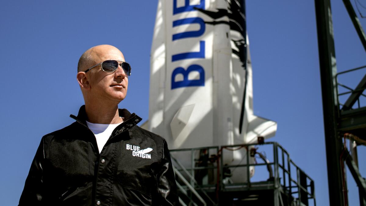 Jeff Bezos stands in front of the New Shepard rocket