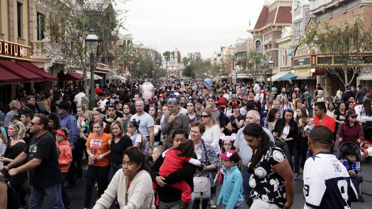 People crowd onto Main Street at Disneyland in Anaheim. The Disneyland Resort is introducing a new annual pass that tries to control crowds by requiring reservations on the most popular days.