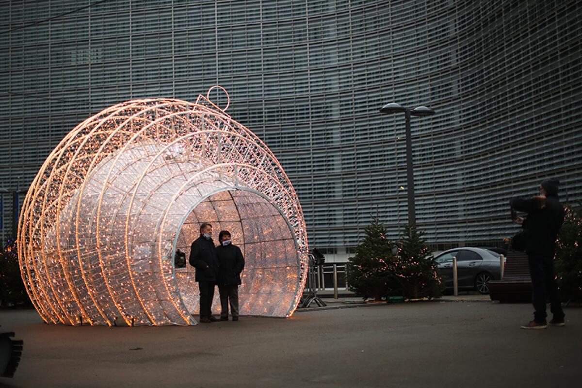 Passers-by take photos next to Christmas decorations outside the European Commission headquarters in Brussels on Saturday.
