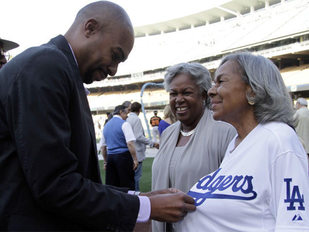 Sharon Robinson looks on as her son, Jesse, helps Rachel Robinson, Jackie¿s widow, with a jersey at Dodger Stadium in May. Sharon will join the Dodgers' board of directors before next season.