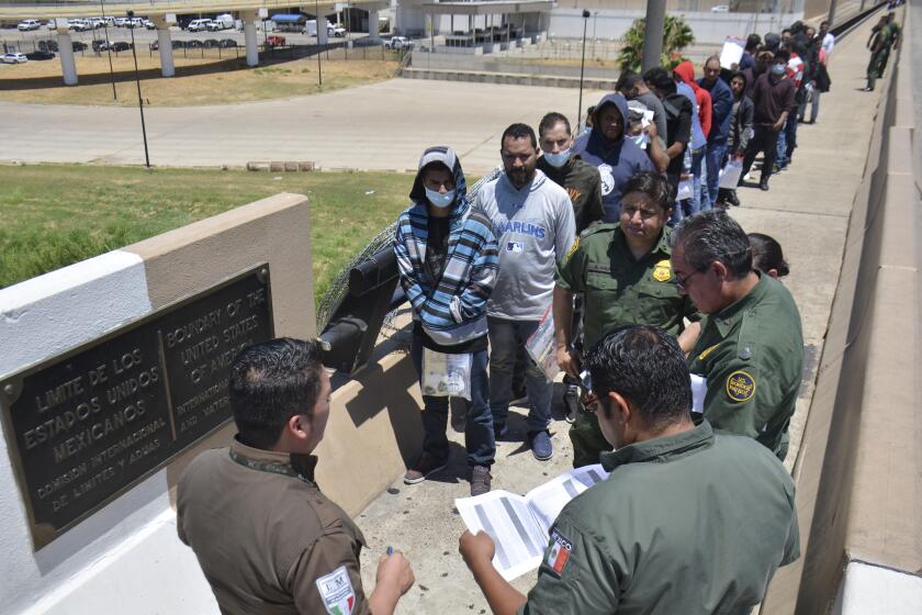 Agentes de la Patrulla de Fronteras de EEUU devuelven a un grupo de migrantes a México por el cruce de Nuevo Laredo el 25 de julio del 2019. (AP Photo/Salvador González)