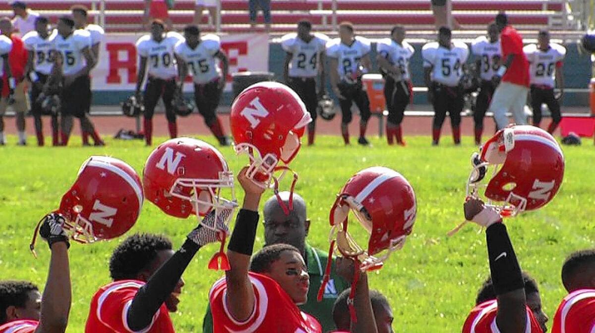 Football players at St. Louis’ Normandy High School observe a moment of silence for Michael Brown last month. Brown graduated from the school on Aug. 1. Eight days later, he was killed.